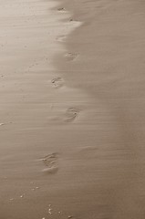 Fototapeta na wymiar Huellas sobre la arena y marcas de agua sobre la ellas