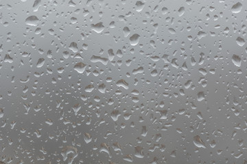 Rain drops on window, against blurry background of a town
