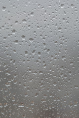 Rain drops on window, against blurry background of a town
