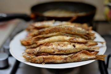 Fried smelt in a frying pan on the table with spices, lime and thyme. Small crispy fish. Selective focus