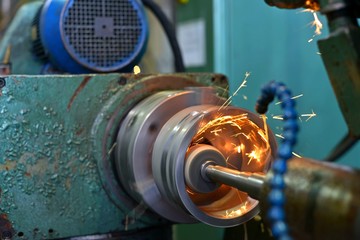 metalworking industry: finishing metal working on lathe grinder machine with flying sparks