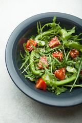 Salad of fresh vegetables and herbs in a plate on a white background, top view.