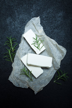 Three pieces of organic feta cheese on the table, rosemary branches.