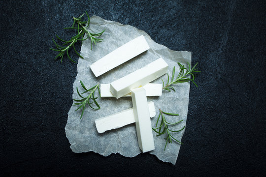 Fresh Feta Cheese with rosemary on black vintage background.