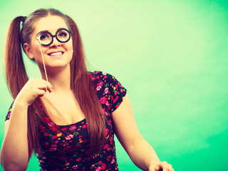 Happy teenage woman holding fake eyeglasses on stick