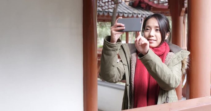 Travel woman taking photo on cellphone in chinese garden