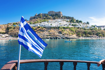 Bay of Lindos, Grrek flag and acropolis of Lindos in background (Rhodes, Greece)