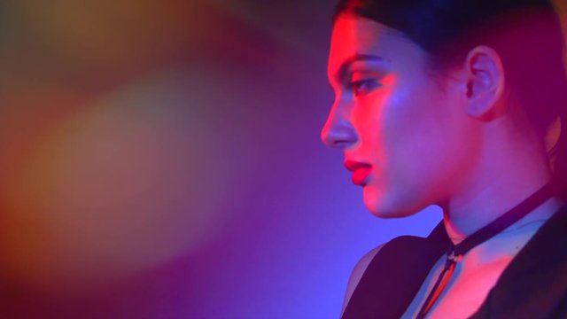 Fashion model woman in colorful bright lights posing in studio, portrait of beautiful sexy girl with trendy makeup. 4K UHD video 3840x2160