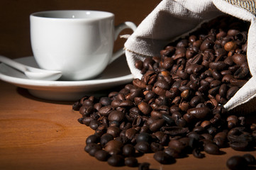 Roasted beans of coffee and a cup on the background