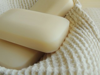 Bars of natural soap on white natural linen waffle texture towel.