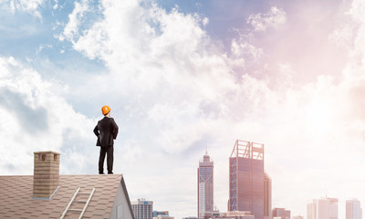 Engineer man standing on roof and looking away. Mixed media