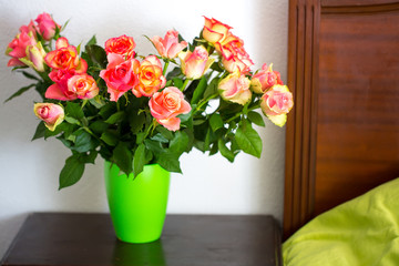 A bouquet of roses in a vase on a bedside table