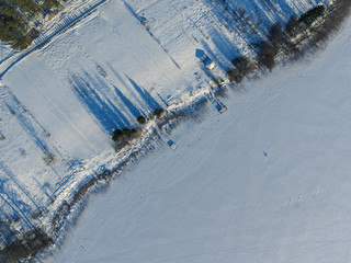 Obraz premium Aerial view over frozen lake cover in white snow with long blue shadows from trees in Latazeris, Lithuania. During cold winter day.