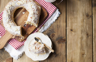 Christmas baking roll with almonds on a wooden table and napkin in a red cage
