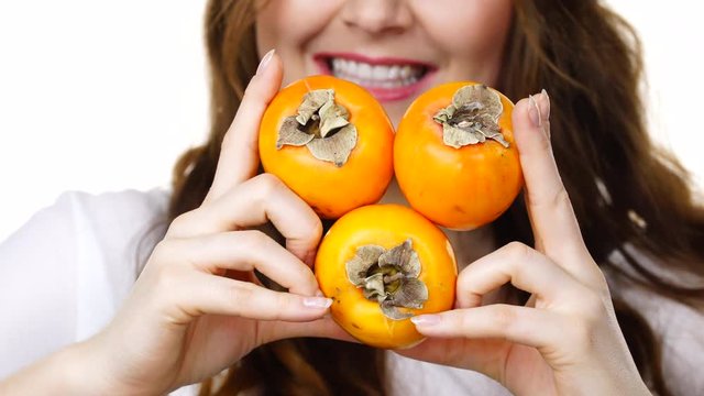 Woman toothy smile brunette girl holding  persimmon kaki fruits in hands, isolated on white. Healthy eating, vegetarian food, diet concept.