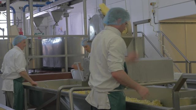 Employees using mahine to mill fresh cheese in cheese making factory