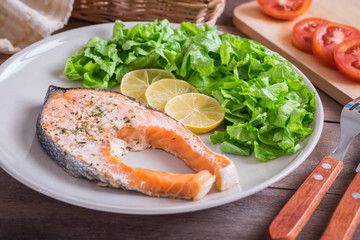 Grilled salmon steak covered with herb on plate .