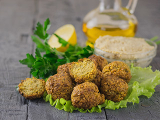 Freshly prepared falafel with tahini paste and olive oil on the dark wooden table.