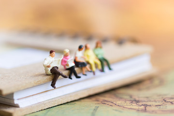 Miniature people sitting on the book using as background education or business concept