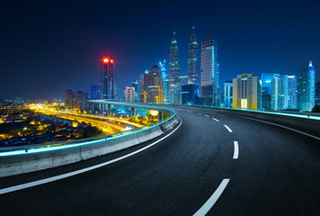 Fototapeta na wymiar Blue neon light design highway overpass with modern city background . Night scene .