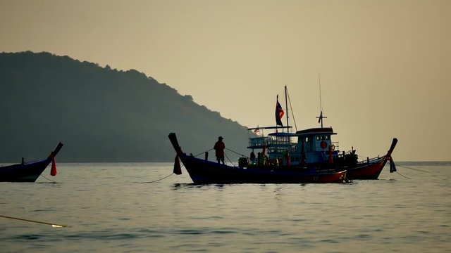 Travel video silhouette Long-tail boats sailing on the andaman  sea with golden light of the Sun  before sunset in travel or transportation concept.