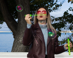 Young pretty girl blows soap bubbles, outdoor  