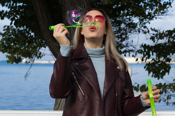 Young pretty girl blows soap bubbles, outdoor  