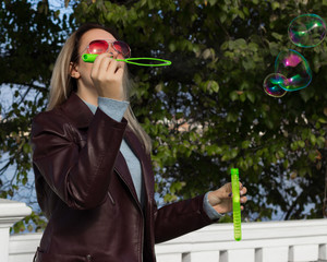 Young pretty girl blows soap bubbles, outdoor  