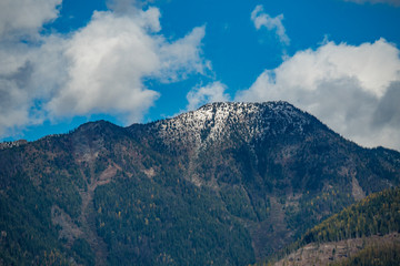 clouds on the blue sky above snow covered peak of the mountain