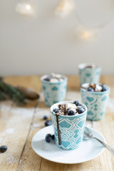 Mousseline cream decorated with wipped mascarpone, chocolate and blueberries arranged in ceramic cups