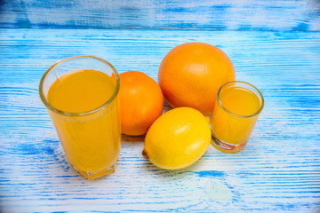 citrus fruits and fresh juice on a light wooden background 