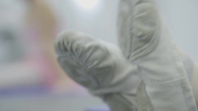 Close-up of children's legs in white dance shoes doing exercises. Children's socks on their feet move back and forth, shod shoes for ballet.