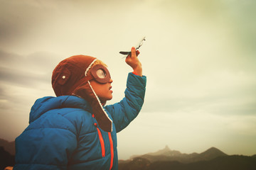 little boy with helmet and glasses play with toy plane on sky