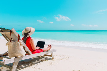 young woman with laptop on tropical beach