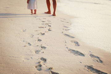 mother and daughter walking on beach leaving footprint in sand - 186183690