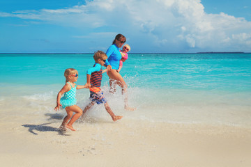 mother with kids play with water run on beach