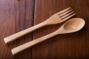 Wooden spoon and fork on wood texture of dining table from top view