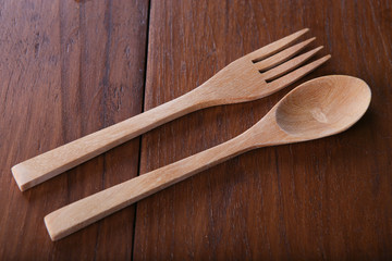 Wooden spoon and fork on wood texture of dining table from top view