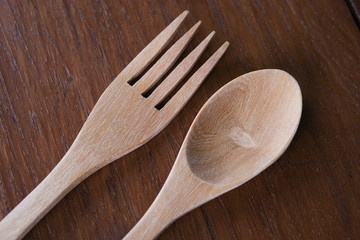 Wooden spoon and fork on wood texture of dining table from top view