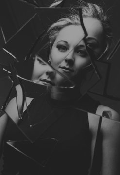 Woman looking at her face in shards of broken mirror artistic conversion