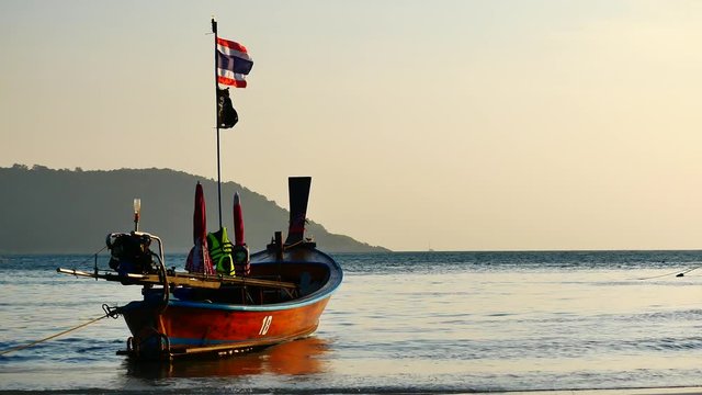 Travel Video long tail boat converted to boat excursions on the bech at andaman sea with golden light of the Sun  before sunset in travel or transportation concept.