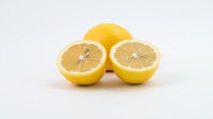 Два лимона, один целый, другой разрезан пополам.