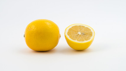 Один целый лимон рядом с отрезанной половинкой лимона.
