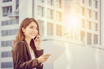 Beautiful smiling business woman with smartphone and paper sheet in hand, Successful and modern smart working concept