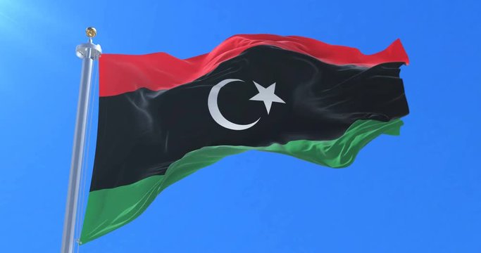 Flag of Libya waving at wind with blue sky in slow, loop
