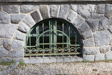 Fototapeta na wymiar Stein Fenster mit grünen Eisen Gitter Bogen