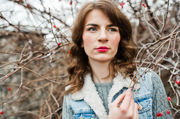 Portrait of brunette girl in jeans jacket at frozen bushes.