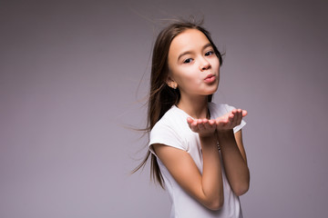 Cute girl is blowing a kiss, isolated over gray background