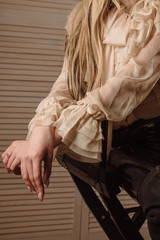 Young femail in vanilla blouse with arms crossed against on background of wood wall. Pose closed for communication, personality psychology, introvert.