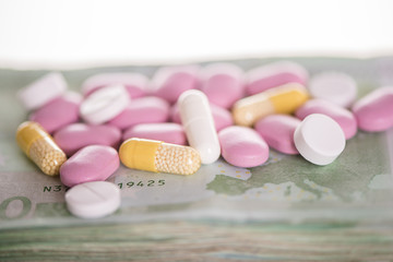 different selection of pills tablets on a hundred euro note and thermomether